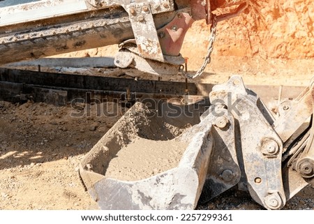 Concrete mixer truck pouring fresh wet concrete into excavators bucket at a construction site