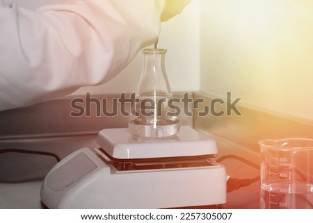 scientist doctor using Magnetic Stirrer adding drops in flask in laboratory. pharmaceutical Royalty-Free Stock Photo #2257305007