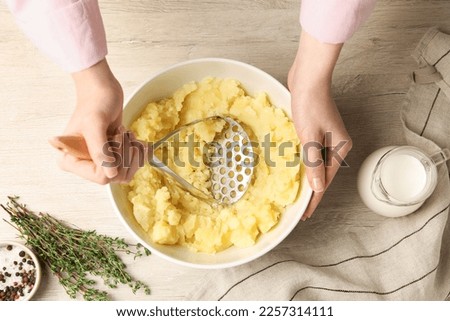 Woman making mashed potato at wooden table, top view Royalty-Free Stock Photo #2257314111