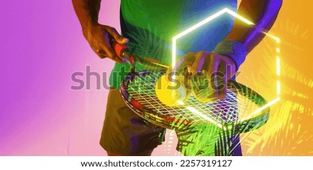 Midsection of african american male player with tennis racket and balls over plants and rectangle. Copy space, composite, sport, competition, shape, playing, nature, hand, match and illuminated.