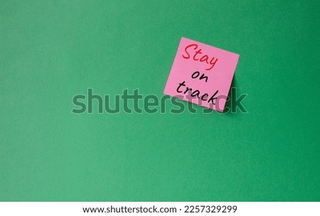 Stay on track symbol. Concept words words Stay on track on pink steaky note. Beautiful green background. Business and Stay on track concept. Copy space.