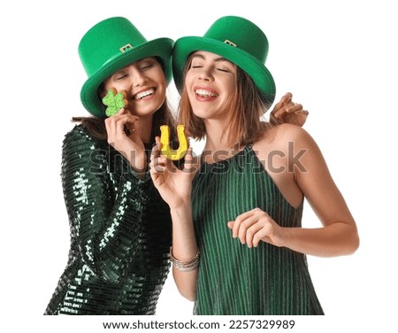 Young women in hats with cookies on white background. St. Patrick's Day celebration