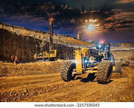 african workers using a grader and a drilling machine in a diamond mine at sunset Royalty-Free Stock Photo #2257330343
