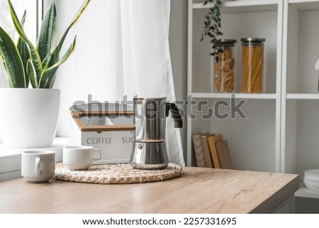 Wicker coaster with geyser coffee maker on kitchen counter near window Royalty-Free Stock Photo #2257331695