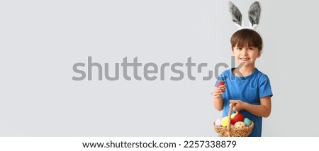 Cute little boy with bunny ears and Easter eggs on grey background with space for text