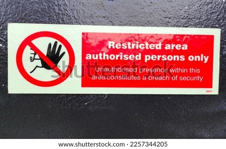 Restricted area sign for those involved only.  Clearly stated that it is a restricted area.  It can be dangerous if approached.  It's a red-cut white sticker.  Mounted on a black wall for clarity.