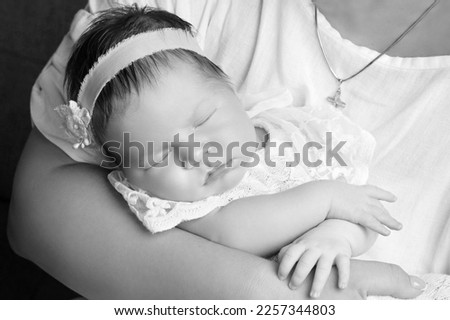 Loving babygirl sleeping in mother's hands. Closeup picture. Happy mother and her slipping smilibg newborn baby girl.