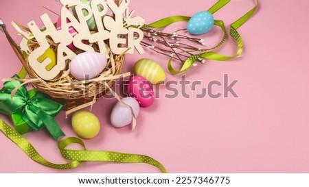 Colorful Easter eggs in the nest with text happy easter on pink background. Easter holiday concept