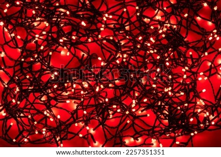 Tangled black wire garlands with red light bulbs on a red background