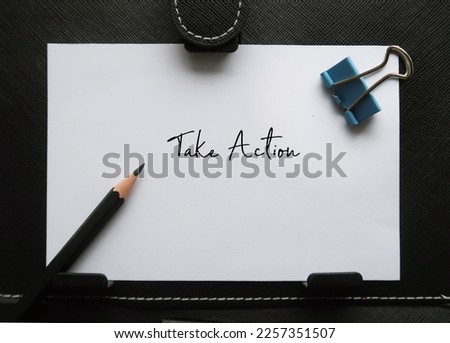 Paper note on black background with handwritten text TAKE ACTION, concept of start really doing the process of doing something in order to deal with a problem or difficult situation, not just planning Royalty-Free Stock Photo #2257351507