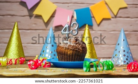Festive cake with a candle with a number  43. Happy birthday background with beautiful decorations.Anniversary party copy space.