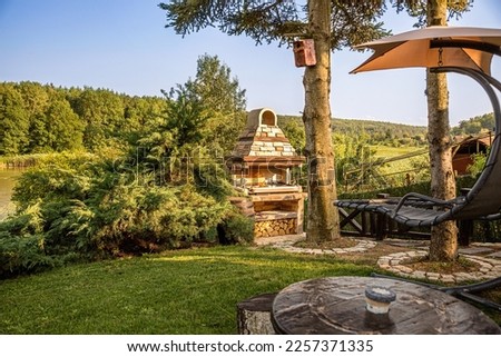 Large Barbecue Open Fireplace with Shelf For Cookout Food. Outdoor BBQ Grill. Open Summer Kitchen. Barbeque Grill Made From Bricks On The Backyard. Royalty-Free Stock Photo #2257371335