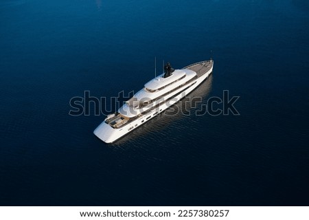 White mega yacht at sunset top view. Large innovative modern yacht anchored in the open sea aerial view. Royalty-Free Stock Photo #2257380257