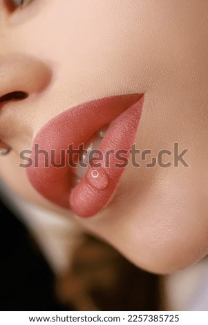 Matte effect of the lips after the procedure of permanent makeup of the lips. On the lips of the girl a drop of oil for moisturizing after the tattoo procedure Royalty-Free Stock Photo #2257385725