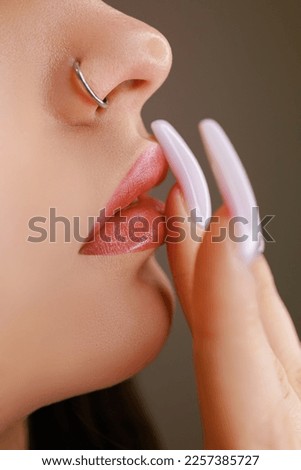 Macro photo of girl's lips after permanent lip makeup. Girl touches lips with fingers after tattoo Royalty-Free Stock Photo #2257385727