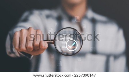 Businessman holding a magnifying glass, showing Audit Document concept,quality assessment management With a checklist, business document evaluation process, market data report analysis and consulting Royalty-Free Stock Photo #2257390147
