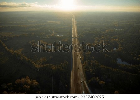 Aerial view of busy american highway with fast moving traffic surrounded by fall forest trees. Interstate transportation concept