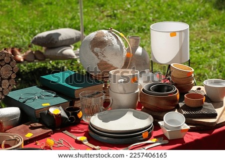 Many different items on table outdoors. Garage sale Royalty-Free Stock Photo #2257406165