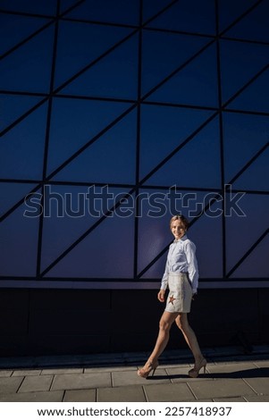a beautiful woman in a skirt with stars walks against a glass wall