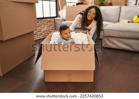 Mother and son playing with cardboard as a car at new home