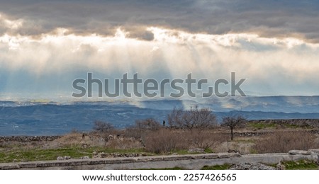 Groups of sunburst rays burst through the Turkey dark clouds lighting up patches of hillside greenery