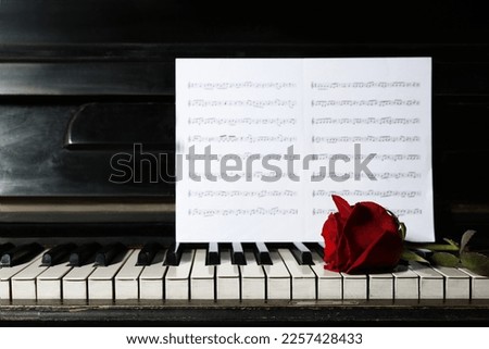 Beautiful red rose and musical notes on piano
