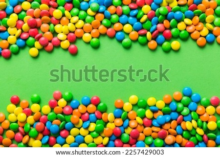Mixed collection of colorful candy, on colored background. Flat lay, top view. frame of colorful chocolate coated candy.