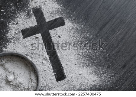 Cross of ashes and bowl filled with ashes on a dark wood background with copy space  Royalty-Free Stock Photo #2257430475