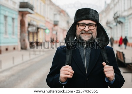 Senior man enjoying a walk in the winter city on the weekend. The concept of city life and recreation.
