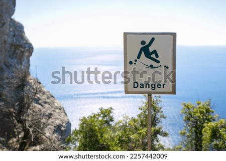 danger warning sign in the mountains, attention danger, falling from a height into the sea, cliff