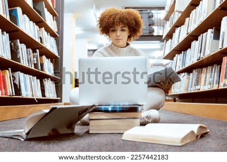 College library learning, laptop and black woman student working on the floor with books. Reading, computer research and online study of a person with test and exam information for university