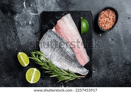 Uncooked Raw Dorado Sea bream fish fillets. Black background. Top view. Royalty-Free Stock Photo #2257455917