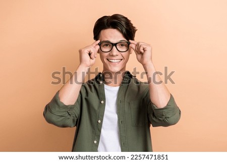 Portrait of positive funny person hands touch eyeglasses beaming smile isolated on beige color background Royalty-Free Stock Photo #2257471851