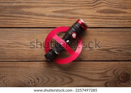 Flashlight with prohibition sign on a wooden table.