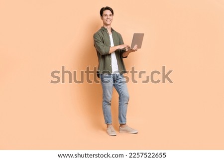 Full body photo of young student guy wearing stylish clothes hold laptop user for distance university education isolated on beige color background