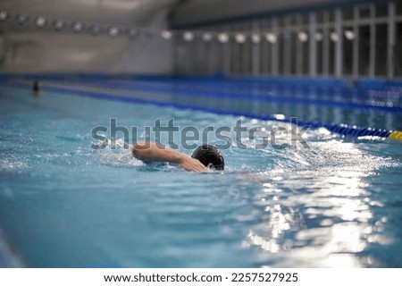 swimmer in the pool, soft focus. swimming in the wave pool, water splashes, bokeh, blur, soft focus. Professional swimmer, race swimming, indoor pool. Sports and fitness cardio exercises.