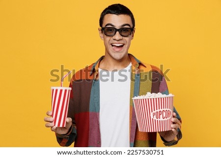 Young ecited cheerful happy fun cool satisfied woman in 3d glasses watch movie film hold bucket of popcorn cup of soda pop in cinema look camera smiling isolated on yellow background studio portrait