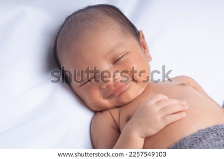 Indonesia baby newborn fall asleep and smiling at the camera with grey blanket and isolated on white background