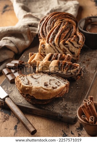 Chocolate Babka or Brioche Bread. Homemade sweet yeast pastry chocolate swirl bread sliced on wooden rustic board. Vertical orientation Royalty-Free Stock Photo #2257571019