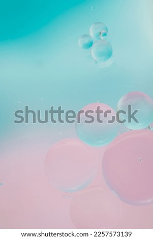 Macro photo of oil bubbles on water on a pink background, fading into blue. Delicate cosmetic background for advertising products. Vertical photo, copy space. Gradient
