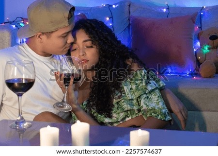 young man looking at his girlfriend while enjoying a glass of wine. young couple having a date at home by candlelight.