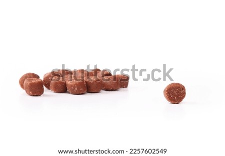 Isolated dog treat with defocused pile of treats. Mini training treat sizes ideal for dog obedience, repetitive tricks and reward. Beef and bacon flavor dog snack. Selective focus. White background. Royalty-Free Stock Photo #2257602549