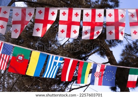 Flag of Georgia, Ukraine, Greece, Latvia, Croatia, Lithuania, Portugal, USA, Italy. Flags of different European countries on rope in street. EU flag. Yellow stars on blue background. Patriotism. Wind 