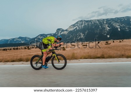 Full length portrait of an active triathlete in sportswear and with a protective helmet riding a bicycle. Selective focus  Royalty-Free Stock Photo #2257615397