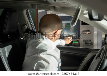 Man in white shirt puts card  in ATM drive. Drive thru cashpoint