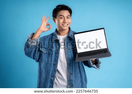 Young asian man using laptop on a blue background