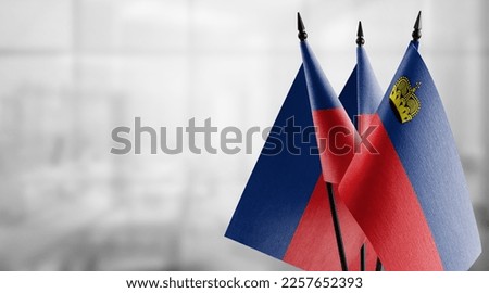 Small flags of the Liechtenstein on an abstract blurry background.