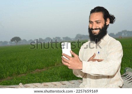 Portrait of an Indian farmer using phone at agriculture field