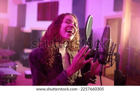 Musician, singing or woman on neon studio microphone, music equipment or practice in night theatre recording. Singer, person or artist on production, voice media or sound performance in light theater Royalty-Free Stock Photo #2257660305