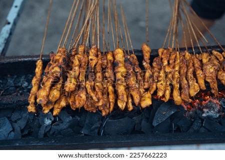 Sate Ayam or Indonesian chicken satays, being grilled using coconut-wood charcoal on traditional earthenware stove.